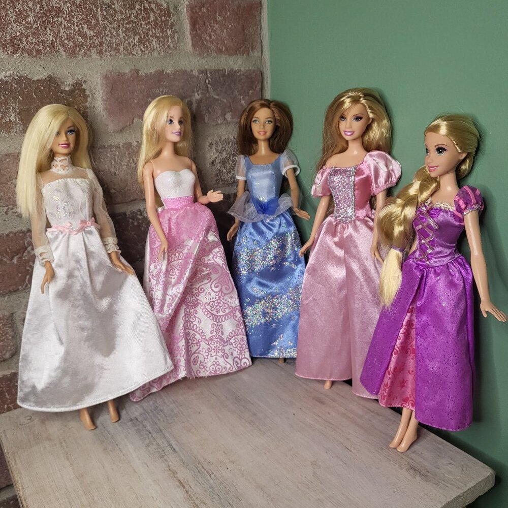 5 Barbie dolls wearing different dresses